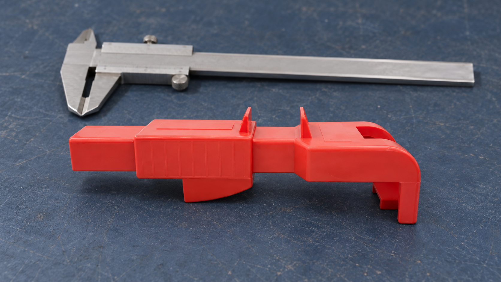 Red adjustable plastic valve-lockout device with a sliding stop structure on an inspection bench.